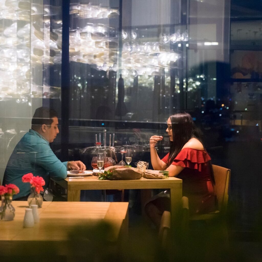 Kobieta i mężczyzna siedzą przy stole w restauracji, prowadzą rozmowę, są uśmiechnięci, nastrojowy klimat restauracji sprzyja rozmowom, randka speed dating w Warszawie u Amora, szybka randka dla singli