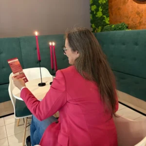 samotna kobieta siedzi przy stole i czyta ulotkę u Amora, speed dating Warszawa u Amora , minirandki Warszawa, szybkie randki Warszawa, dreamdate Warszawa, jak poznać kogoś